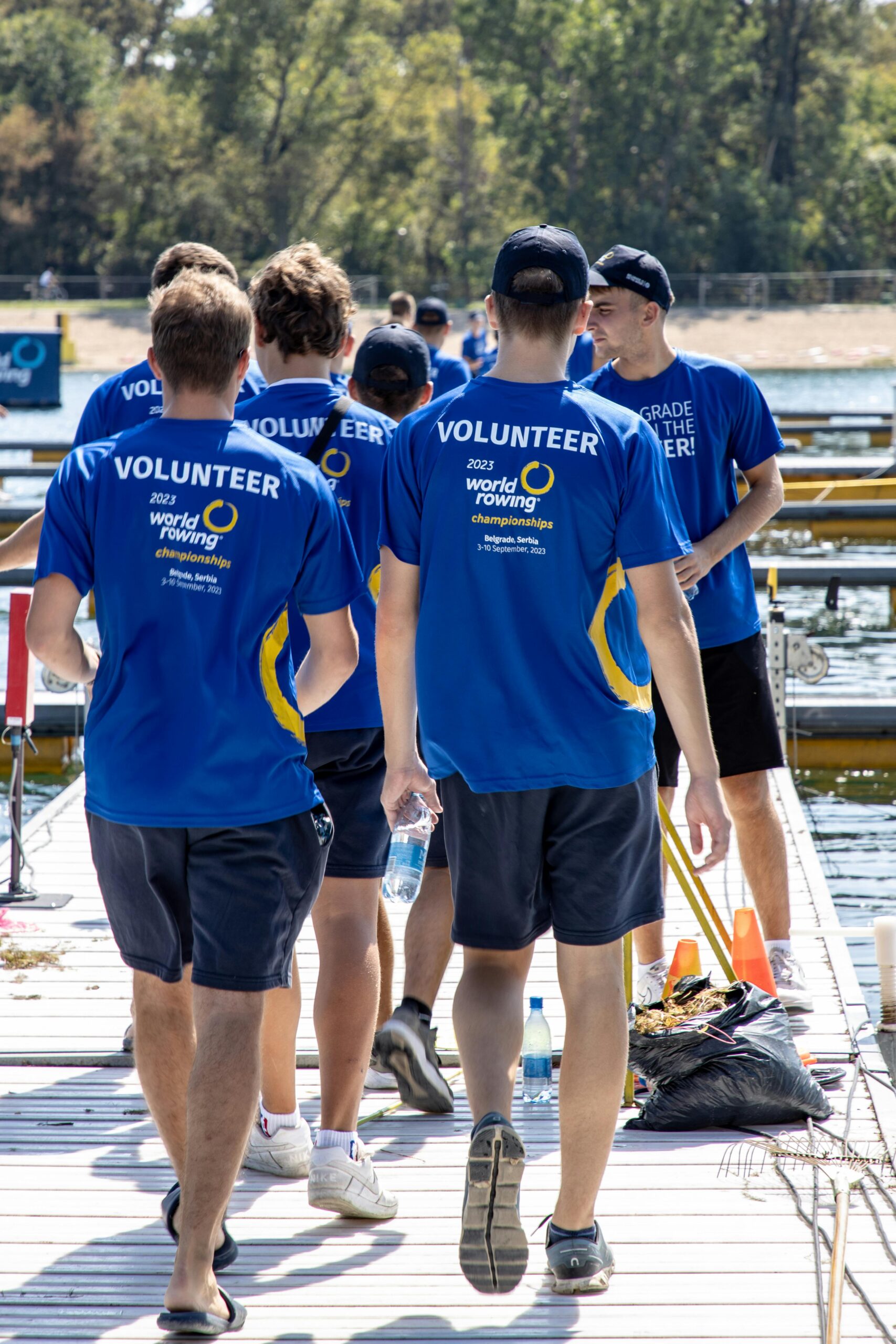 Group of volunteers at the 2023 World Rowing Championships, walking along a dock.